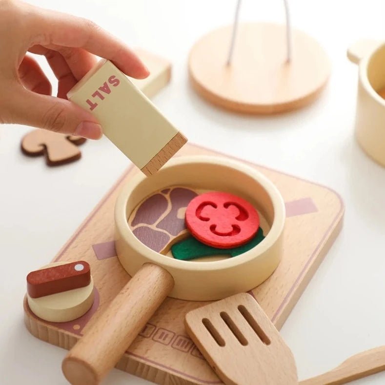 Hand holding a salt shaker over a wooden toy from the Wooden and Silicone Kitchenware Set for kids, promoting imaginative play and fine-motor skill development.